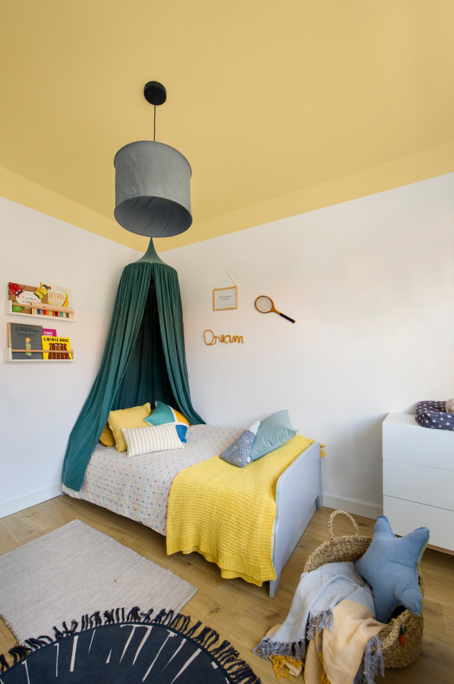 Contemporary gender-neutral kids' bedroom in Barcelona with white walls, medium hardwood floors and brown floor for kids 4-10 years old.