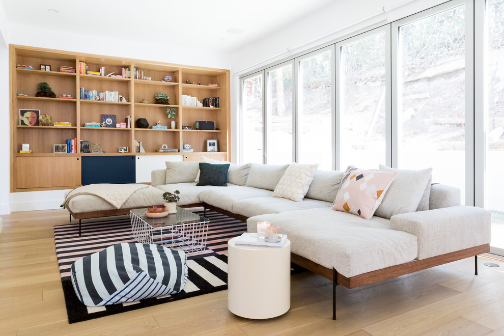 This is an example of a large midcentury open concept living room in Los Angeles with white walls, light hardwood floors and a wall-mounted tv.