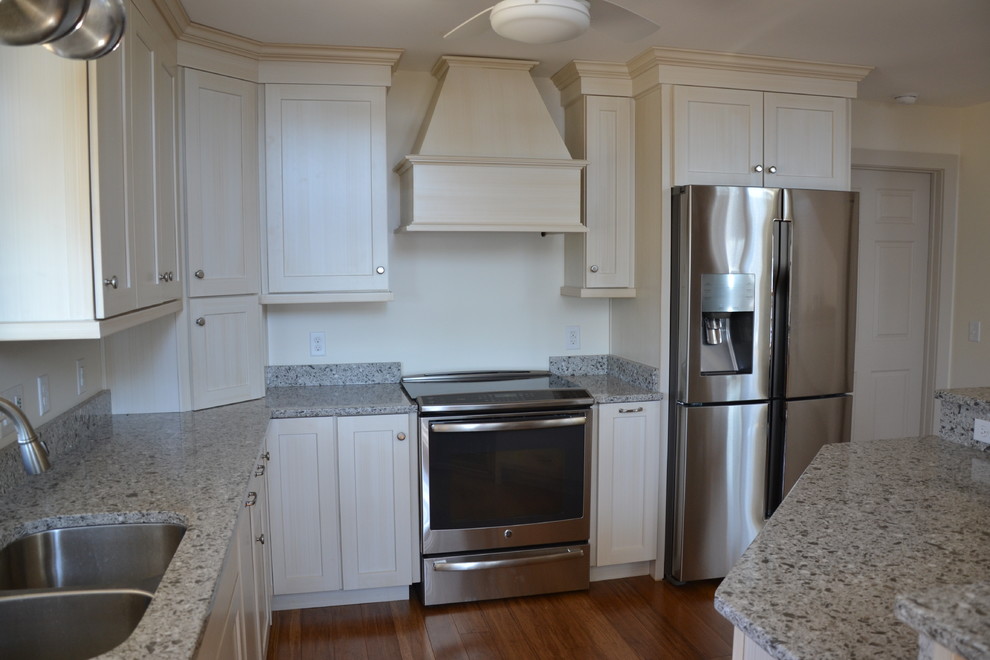 Example of a mid-sized transitional l-shaped medium tone wood floor eat-in kitchen design with a double-bowl sink, shaker cabinets, white cabinets, quartz countertops, stainless steel appliances and an island