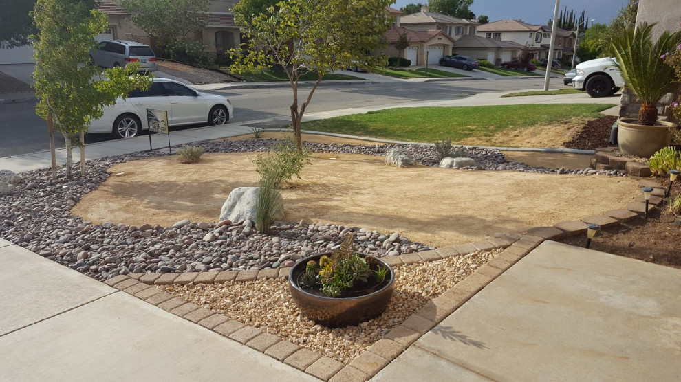 Medium sized front xeriscape full sun garden for summer in Los Angeles with a desert look and decorative stones.