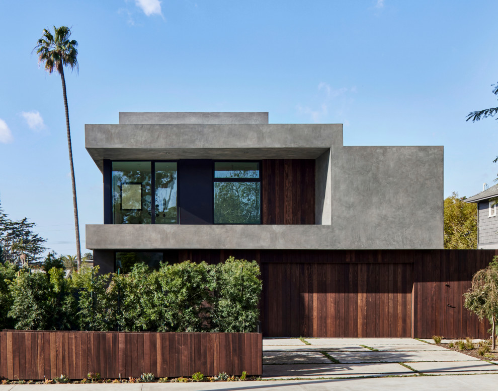 Modelo de fachada de casa gris minimalista grande a niveles con revestimiento de estuco y tejado plano