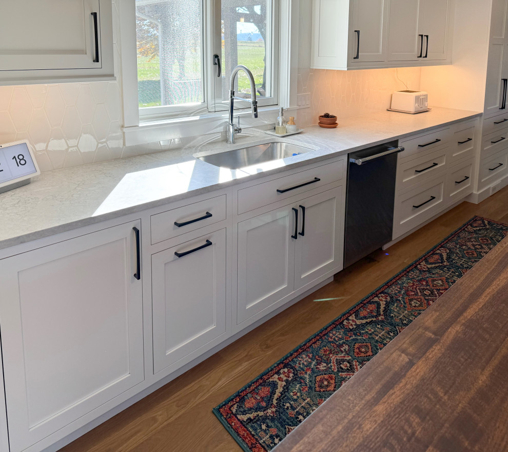 Eat-in kitchen - mid-sized transitional l-shaped medium tone wood floor and brown floor eat-in kitchen idea with an undermount sink, shaker cabinets, white cabinets, white backsplash, an island, white countertops and stainless steel appliances