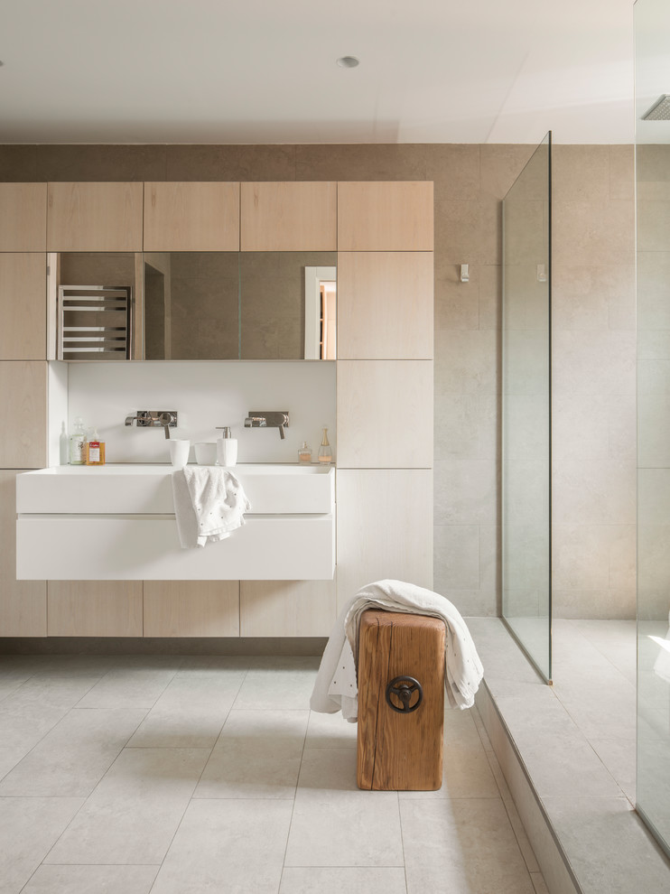 This is an example of a large contemporary master bathroom in Barcelona with white cabinets, a double shower, a one-piece toilet, gray tile, ceramic tile, grey walls, ceramic floors, a wall-mount sink, solid surface benchtops, grey floor, an open shower, white benchtops and flat-panel cabinets.