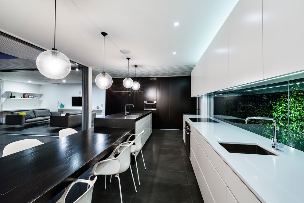 Photo of a mid-sized contemporary galley eat-in kitchen in Sydney with an undermount sink, flat-panel cabinets, white cabinets, with island, quartz benchtops, glass sheet splashback, stainless steel appliances, ceramic floors and black floor.