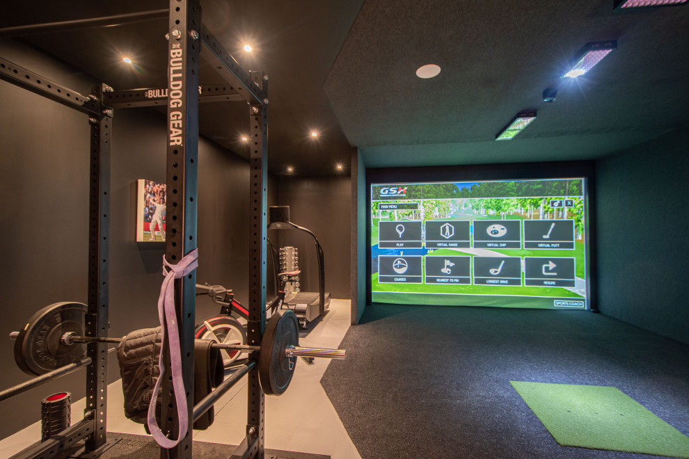 Large modern enclosed games room with a game room, black walls, carpet, a wall mounted tv and grey floors.