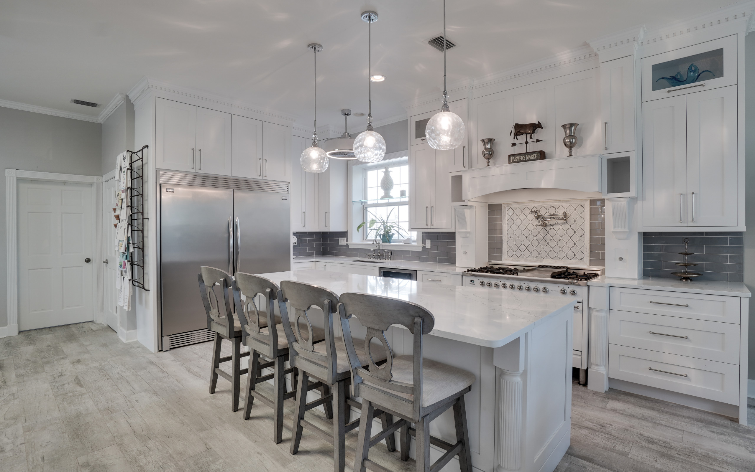 Example of a cottage l-shaped gray floor kitchen design in Orlando with an undermount sink, shaker cabinets, white cabinets, gray backsplash, white appliances, an island and white countertops