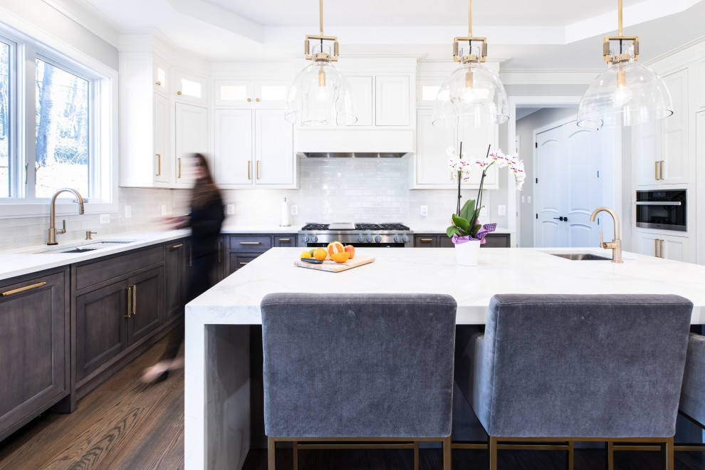 Photo of a large transitional u-shaped open plan kitchen in DC Metro with a single-bowl sink, beaded inset cabinets, white cabinets, quartz benchtops, white splashback, ceramic splashback, panelled appliances, dark hardwood floors, with island, brown floor, white benchtop and recessed.