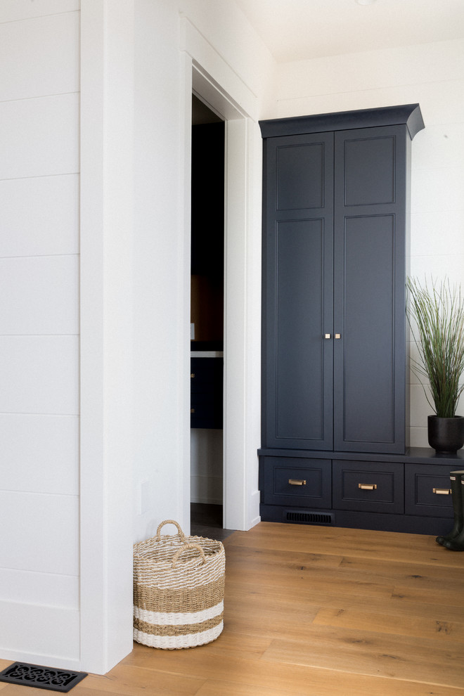 Photo of a large transitional mudroom in Toronto with white walls, light hardwood floors and brown floor.