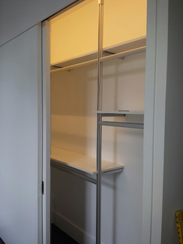Photo of a small modern gender-neutral built-in wardrobe in New York with open cabinets and white cabinets.