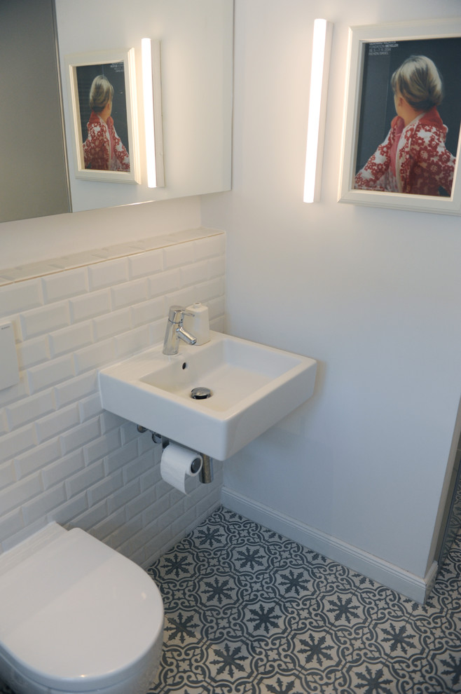 Mid-sized contemporary bathroom in Berlin with a drop-in tub, a curbless shower, a wall-mount toilet, white tile, porcelain tile, white walls, cement tiles, a wall-mount sink and grey floor.