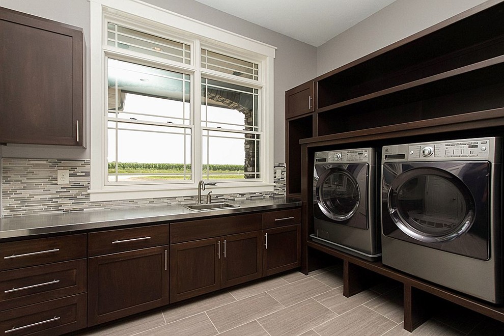 Inspiration for a modern l-shaped laundry room in Other with an undermount sink, open cabinets, dark wood cabinets, stainless steel benchtops, grey walls, porcelain floors and a side-by-side washer and dryer.