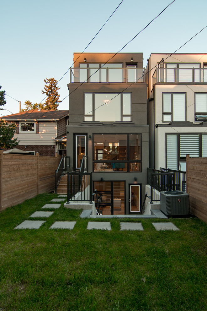 Mid-sized contemporary three-storey stucco grey townhouse exterior in Toronto with a flat roof.