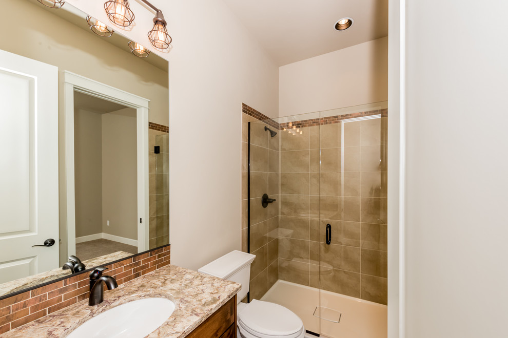 Design ideas for a mid-sized traditional 3/4 bathroom in Portland with medium wood cabinets, an alcove tub, a shower/bathtub combo, a one-piece toilet, brown tile, beige walls, an undermount sink, granite benchtops and a hinged shower door.