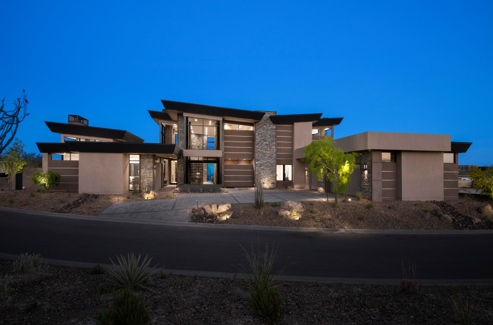 Inspiration for an expansive modern three-storey house exterior in Phoenix with stone veneer and a butterfly roof.