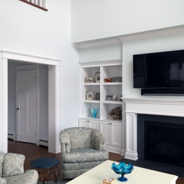 Mid-sized transitional open concept family room in New York with blue walls, medium hardwood floors, a standard fireplace, a plaster fireplace surround and a wall-mounted tv.