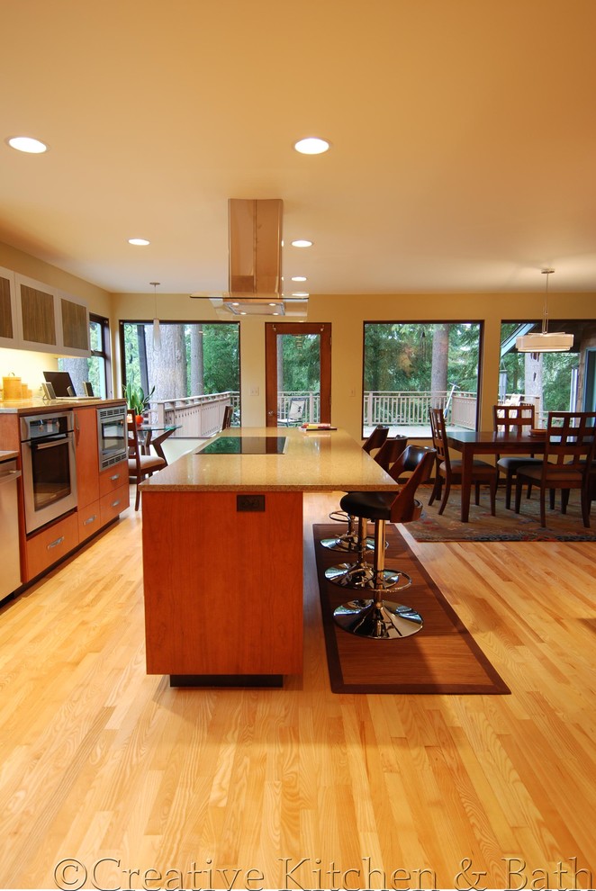 Inspiration for a mid-sized contemporary single-wall eat-in kitchen in Seattle with flat-panel cabinets, light wood cabinets, granite benchtops, light hardwood floors and with island.