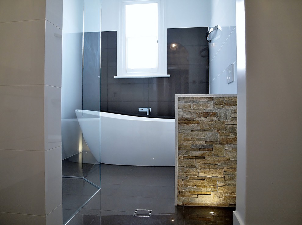 This is an example of a mid-sized contemporary master bathroom in Adelaide with a freestanding tub, an open shower, a wall-mount toilet and porcelain tile.