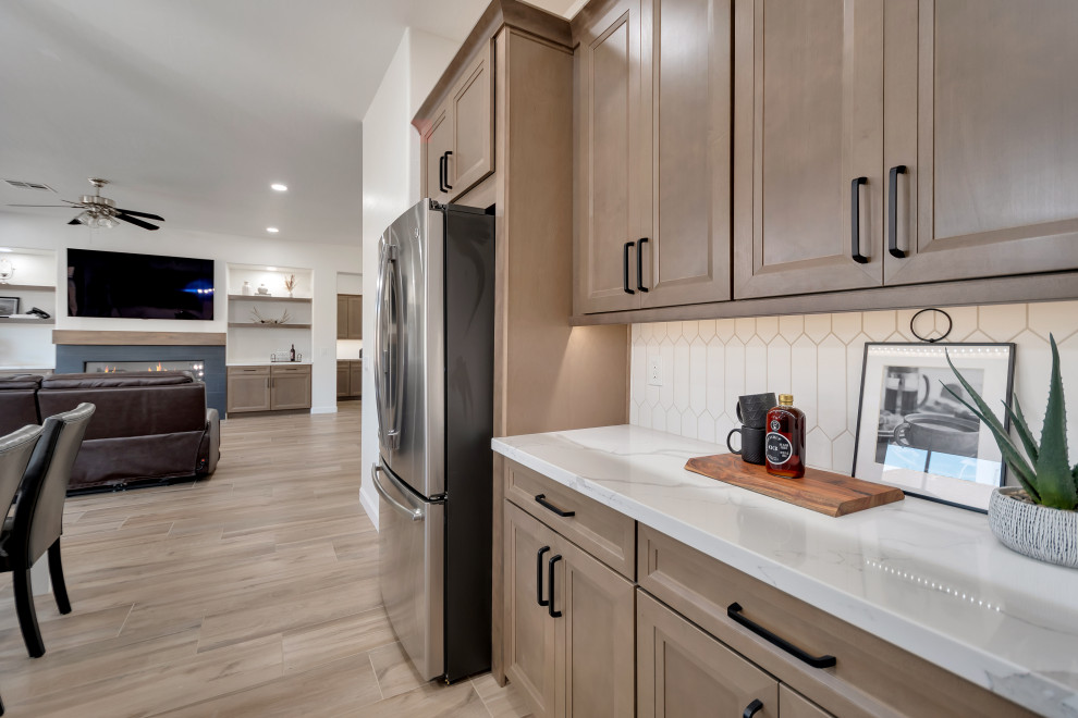 Mid-sized transitional u-shaped ceramic tile and brown floor eat-in kitchen photo in Phoenix with beaded inset cabinets, brown cabinets, quartzite countertops, white backsplash, ceramic backsplash, an island and white countertops