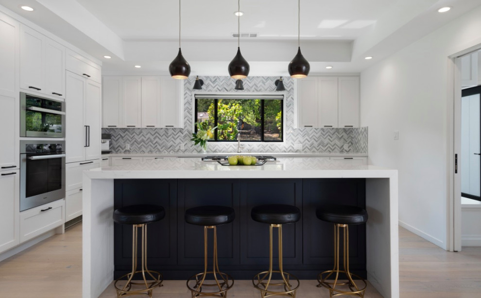 Inspiration for a mid-sized country u-shaped kitchen in San Francisco with shaker cabinets, white cabinets, quartz benchtops, panelled appliances, light hardwood floors, with island and white benchtop.