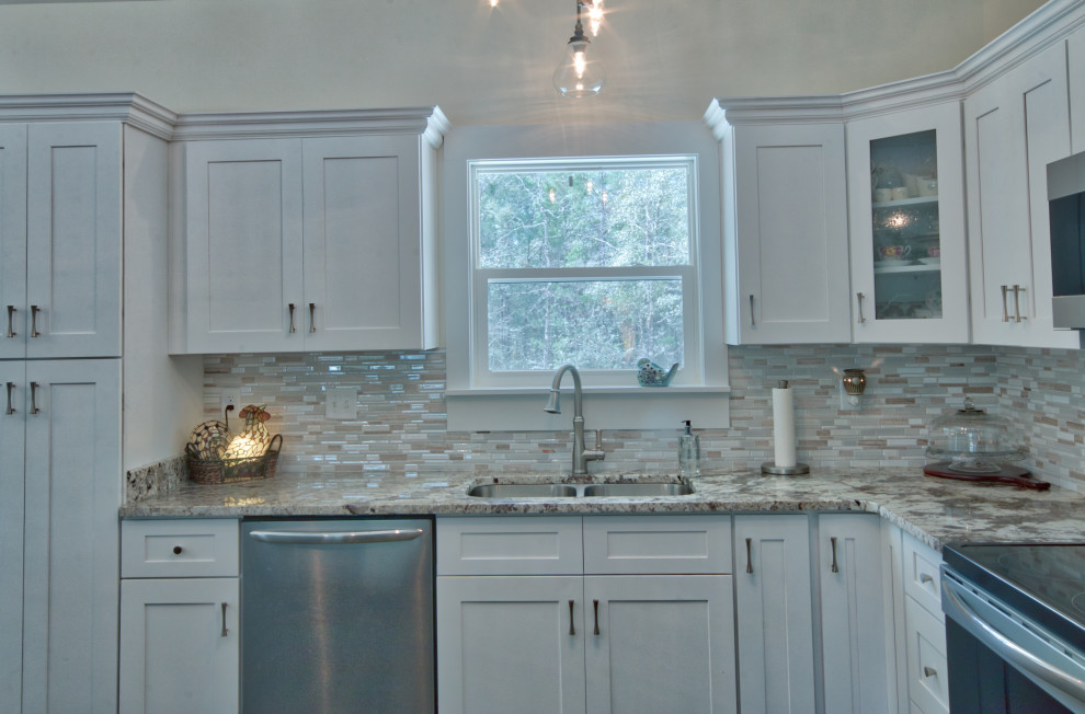 Inspiration for a mid-sized l-shaped eat-in kitchen remodel with an undermount sink, shaker cabinets, yellow cabinets, granite countertops, glass tile backsplash, stainless steel appliances, an island and white countertops