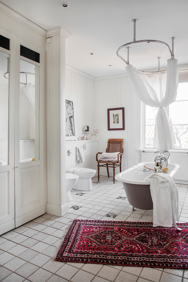 This is an example of a mid-sized scandinavian master bathroom in Stockholm with a claw-foot tub, a bidet, white walls, ceramic tile, ceramic floors and a shower curtain.