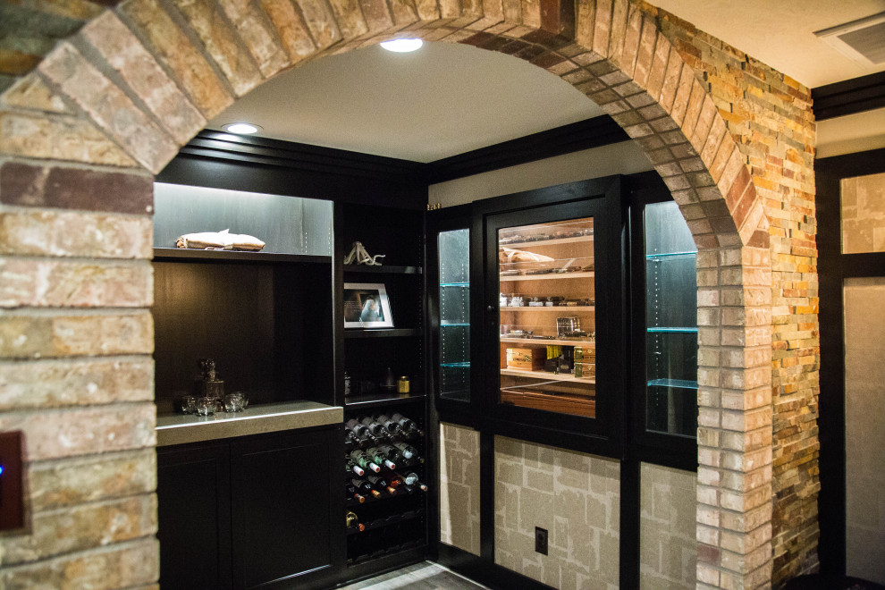 Стильный дизайн: подземный, большой подвал в современном стиле с домашним баром, коричневыми стенами, полом из ламината, стандартным камином, фасадом камина из каменной кладки, коричневым полом и кирпичными стенами - последний тренд