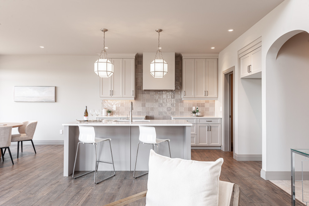 Open concept kitchen - small transitional galley laminate floor and brown floor open concept kitchen idea in Toronto with a double-bowl sink, recessed-panel cabinets, beige cabinets, quartz countertops, beige backsplash, porcelain backsplash, stainless steel appliances, an island and white countertops