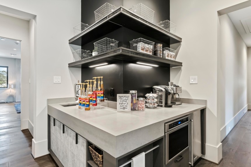 Inspiration for a small industrial l-shaped wet bar in Houston with an undermount sink, flat-panel cabinets, grey cabinets, quartz benchtops, black splashback, painted wood floors, brown floor and grey benchtop.