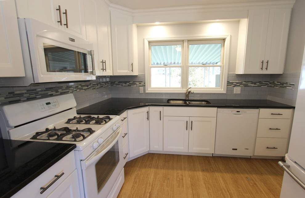 Photo of a small transitional u-shaped eat-in kitchen in Cleveland with an undermount sink, flat-panel cabinets, white cabinets, granite benchtops, blue splashback, subway tile splashback, white appliances and no island.