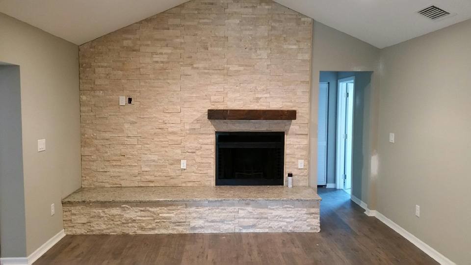 This is an example of a mid-sized contemporary open concept family room in Tampa with grey walls, laminate floors, a standard fireplace, a stone fireplace surround, a wall-mounted tv and brown floor.