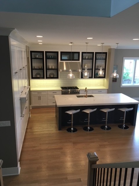 Inspiration for a huge transitional l-shaped light wood floor and beige floor home design remodel in Chicago with an undermount sink, glass-front cabinets, white cabinets, quartz countertops, white backsplash, ceramic backsplash, paneled appliances, an island and white countertops