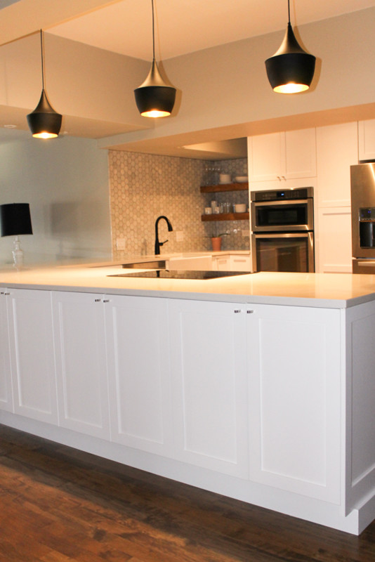 Large scandinavian u-shaped eat-in kitchen in Chicago with flat-panel cabinets, white cabinets, laminate benchtops, white splashback, ceramic splashback, stainless steel appliances, medium hardwood floors, a farmhouse sink, a peninsula and brown floor.