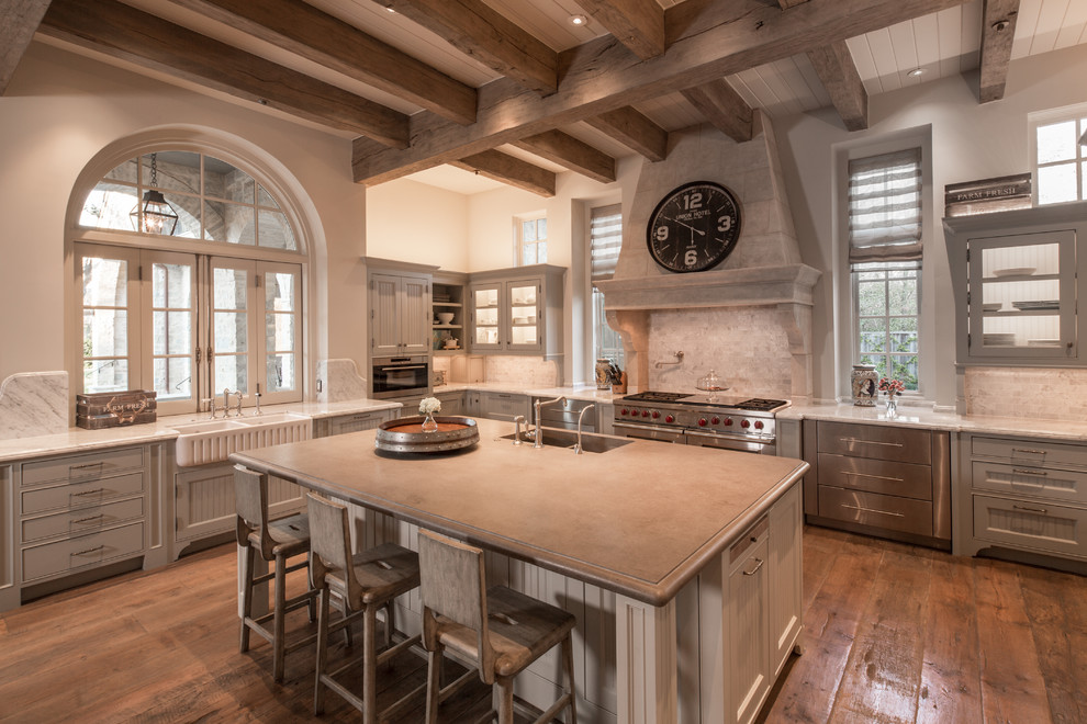 Traditional u-shaped separate kitchen in Houston with a farmhouse sink, grey cabinets, beige splashback, stainless steel appliances, medium hardwood floors, with island, orange floor and beaded inset cabinets.