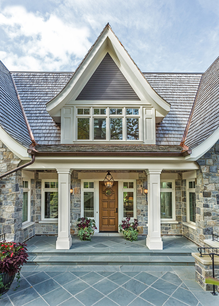 Expansive traditional grey exterior in Milwaukee with stone veneer and a gable roof.