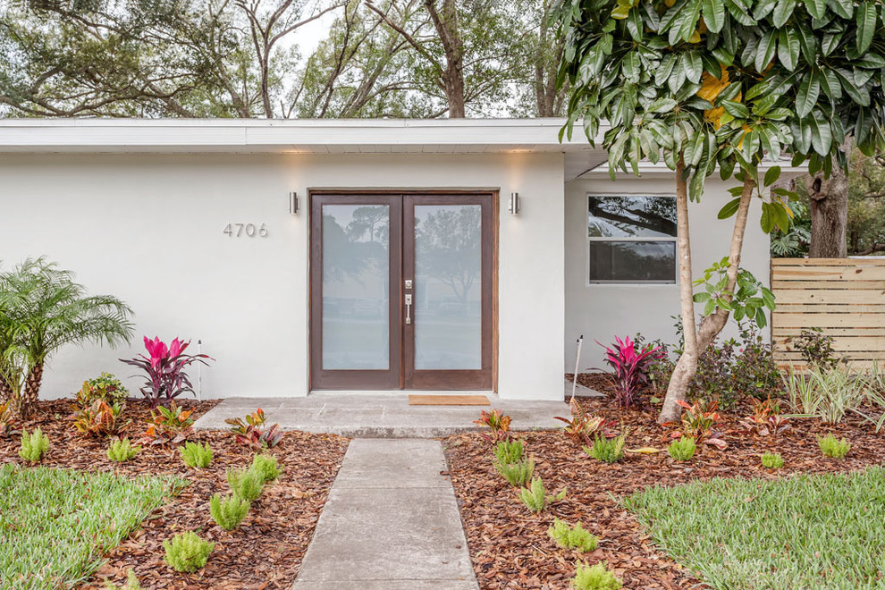 This is an example of a mid-sized midcentury one-storey concrete grey exterior in Tampa with a flat roof.