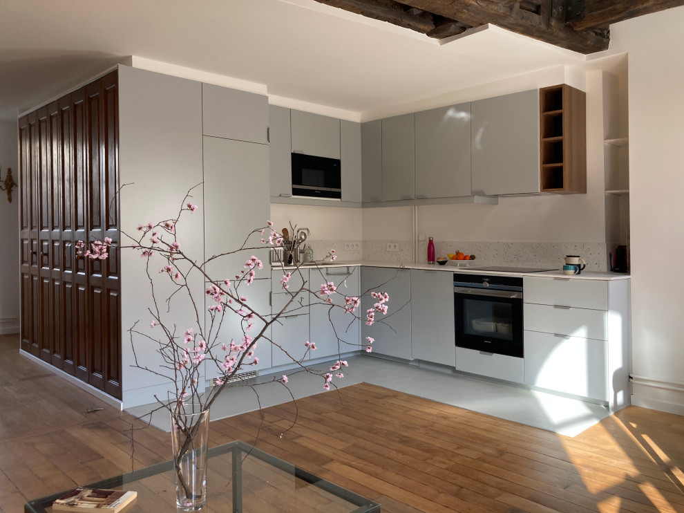Mid-sized contemporary l-shaped eat-in kitchen in Paris with an integrated sink, beaded inset cabinets, grey cabinets, terrazzo benchtops, multi-coloured splashback, black appliances, linoleum floors, grey floor, multi-coloured benchtop and wood.
