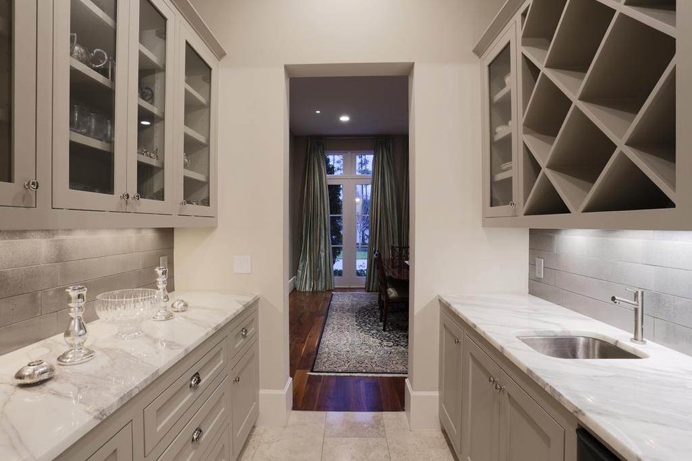 Mid-sized modern galley wet bar in Houston with an undermount sink, recessed-panel cabinets, beige cabinets, marble benchtops, grey splashback and beige floor.