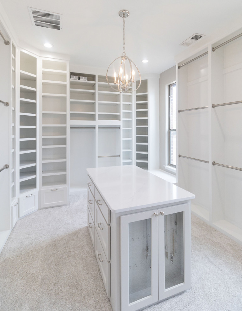 This is an example of an expansive transitional gender-neutral walk-in wardrobe in Dallas with shaker cabinets, white cabinets, carpet and white floor.