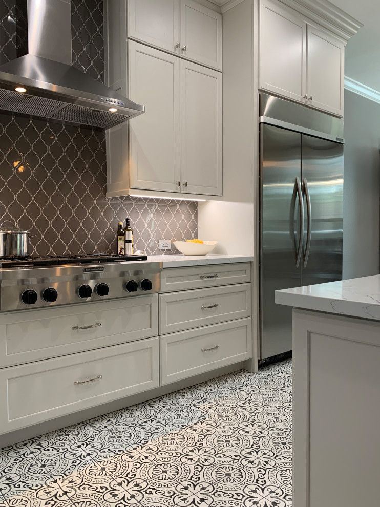 Example of a transitional l-shaped porcelain tile and multicolored floor kitchen design in Houston with a farmhouse sink, recessed-panel cabinets, white cabinets, quartz countertops, gray backsplash, ceramic backsplash, stainless steel appliances, an island and white countertops