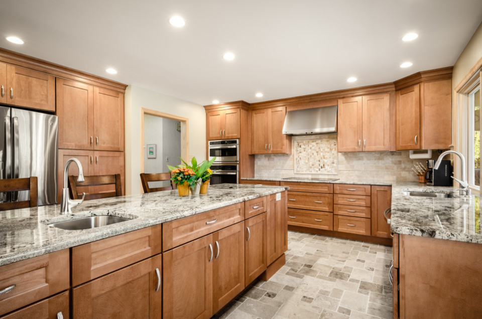Photo of a large transitional u-shaped eat-in kitchen in San Diego with an undermount sink, shaker cabinets, light wood cabinets, granite benchtops, beige splashback, porcelain splashback, stainless steel appliances, porcelain floors, with island, grey floor and multi-coloured benchtop.