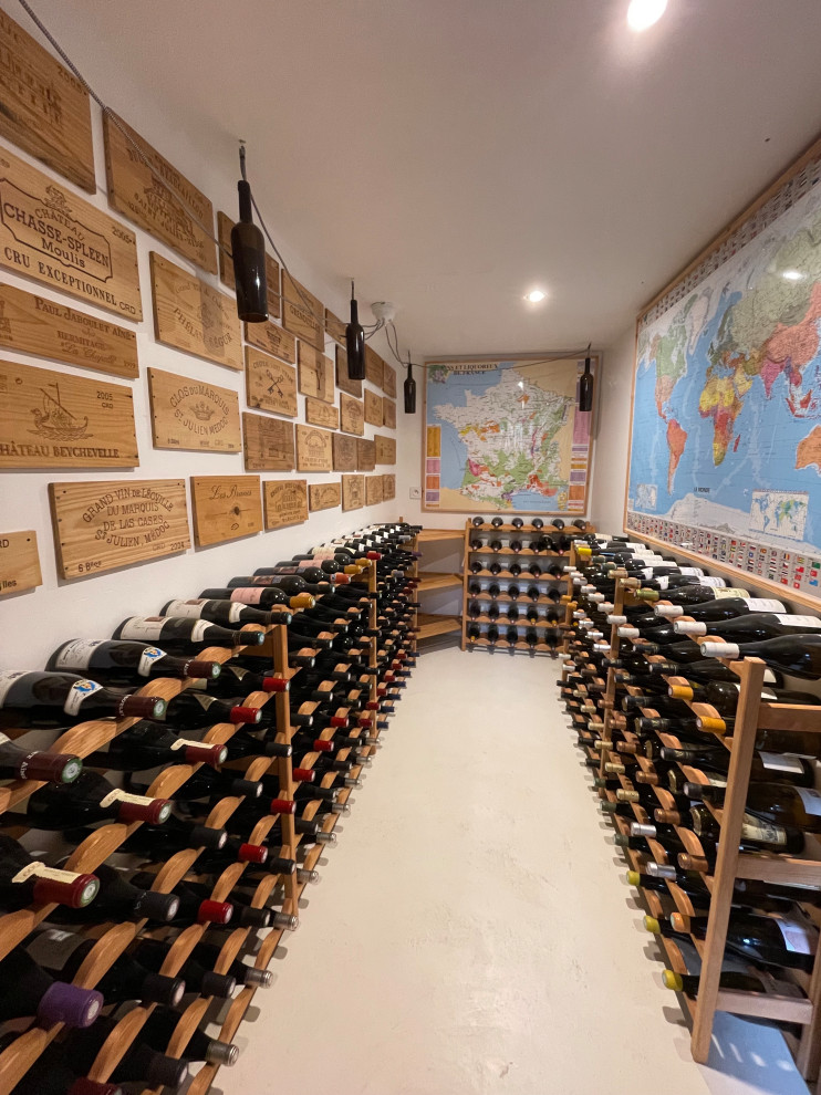 Photo of a mid-sized modern wine cellar in Other with concrete floors, display racks and white floor.