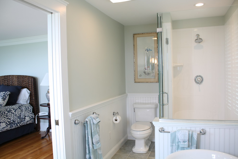 Photo of a beach style bathroom in Boston with a vessel sink, white cabinets, a freestanding tub, a corner shower, a two-piece toilet and ceramic tile.