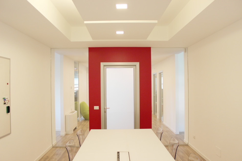 Großes Modernes Arbeitszimmer mit Arbeitsplatz, weißer Wandfarbe, hellem Holzboden, freistehendem Schreibtisch und eingelassener Decke in Mailand