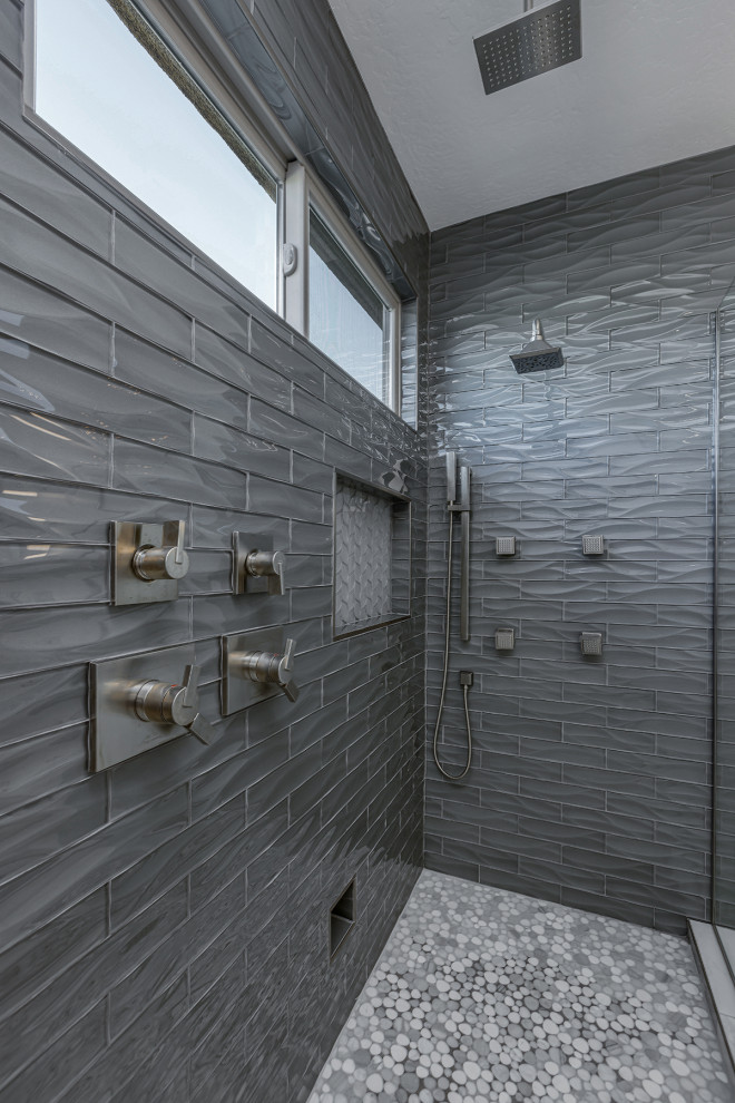 Cette photo montre une grande douche en alcôve principale chic avec un carrelage gris, un carrelage en pâte de verre, un mur gris, un sol en galet, un sol multicolore, une cabine de douche à porte battante et une niche.