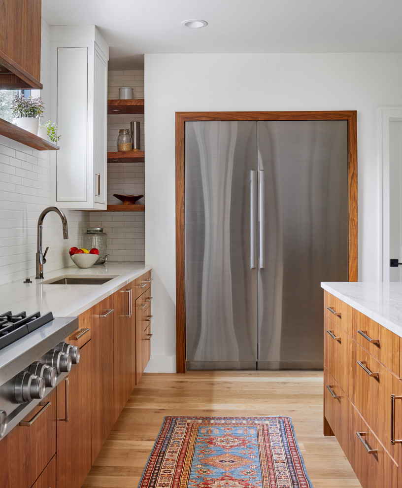 Inspiration for a large scandinavian u-shaped light wood floor open concept kitchen remodel in Denver with an undermount sink, flat-panel cabinets, medium tone wood cabinets, quartzite countertops, white backsplash, ceramic backsplash, stainless steel appliances, an island and white countertops