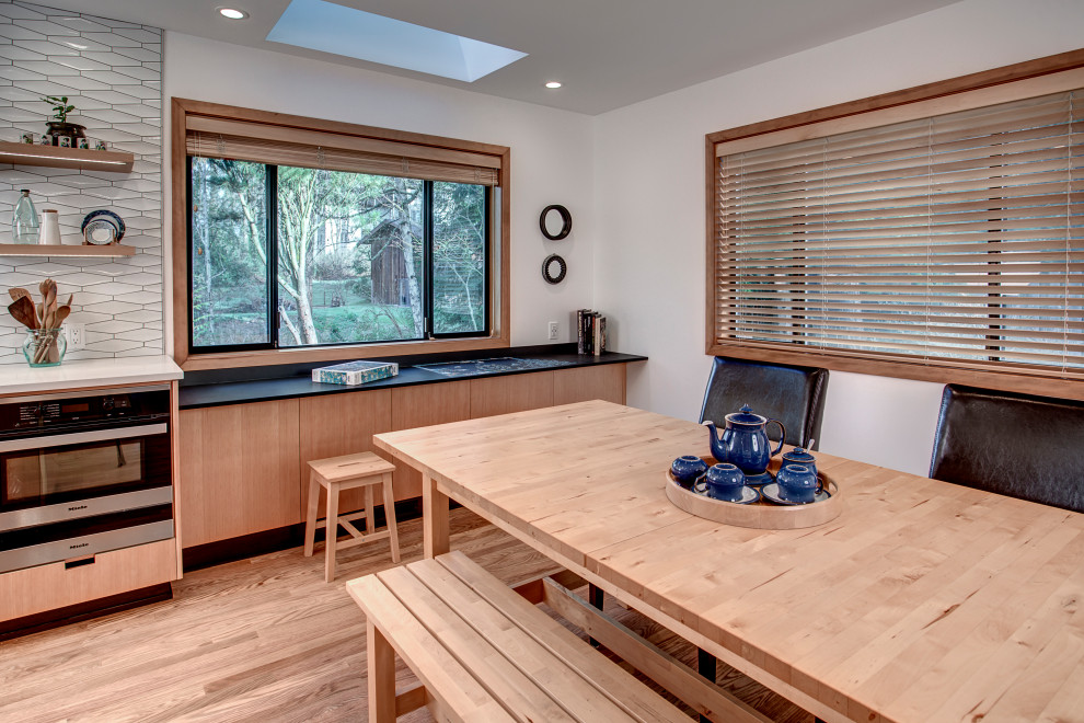Example of a large minimalist light wood floor kitchen design in Seattle with an undermount sink, flat-panel cabinets, light wood cabinets, quartz countertops, white backsplash, porcelain backsplash, stainless steel appliances, an island and white countertops