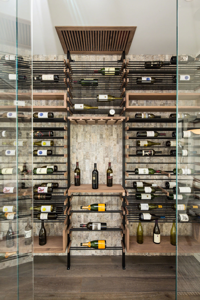 Photo of a small contemporary wine cellar in Los Angeles with medium hardwood floors, display racks and grey floor.