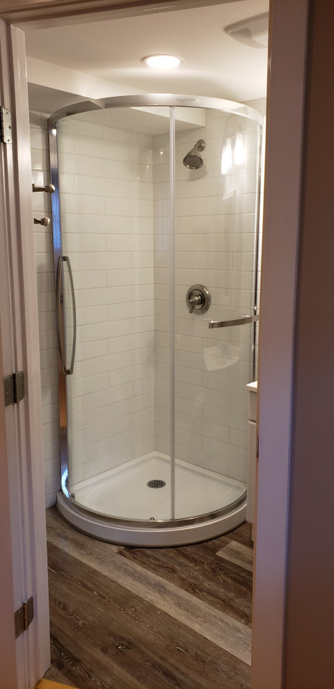 Small 3/4 white tile and ceramic tile vinyl floor, brown floor and single-sink alcove shower photo with white cabinets and white walls