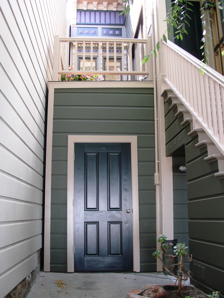 This is an example of a small traditional entry hall in San Francisco with green walls, concrete floors, a single front door and a black front door.