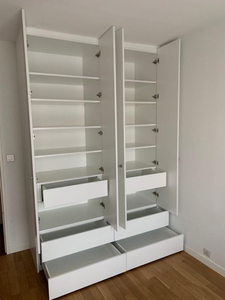 Photo of a small traditional gender-neutral walk-in wardrobe in Paris with beaded inset cabinets, white cabinets, medium hardwood floors and brown floor.